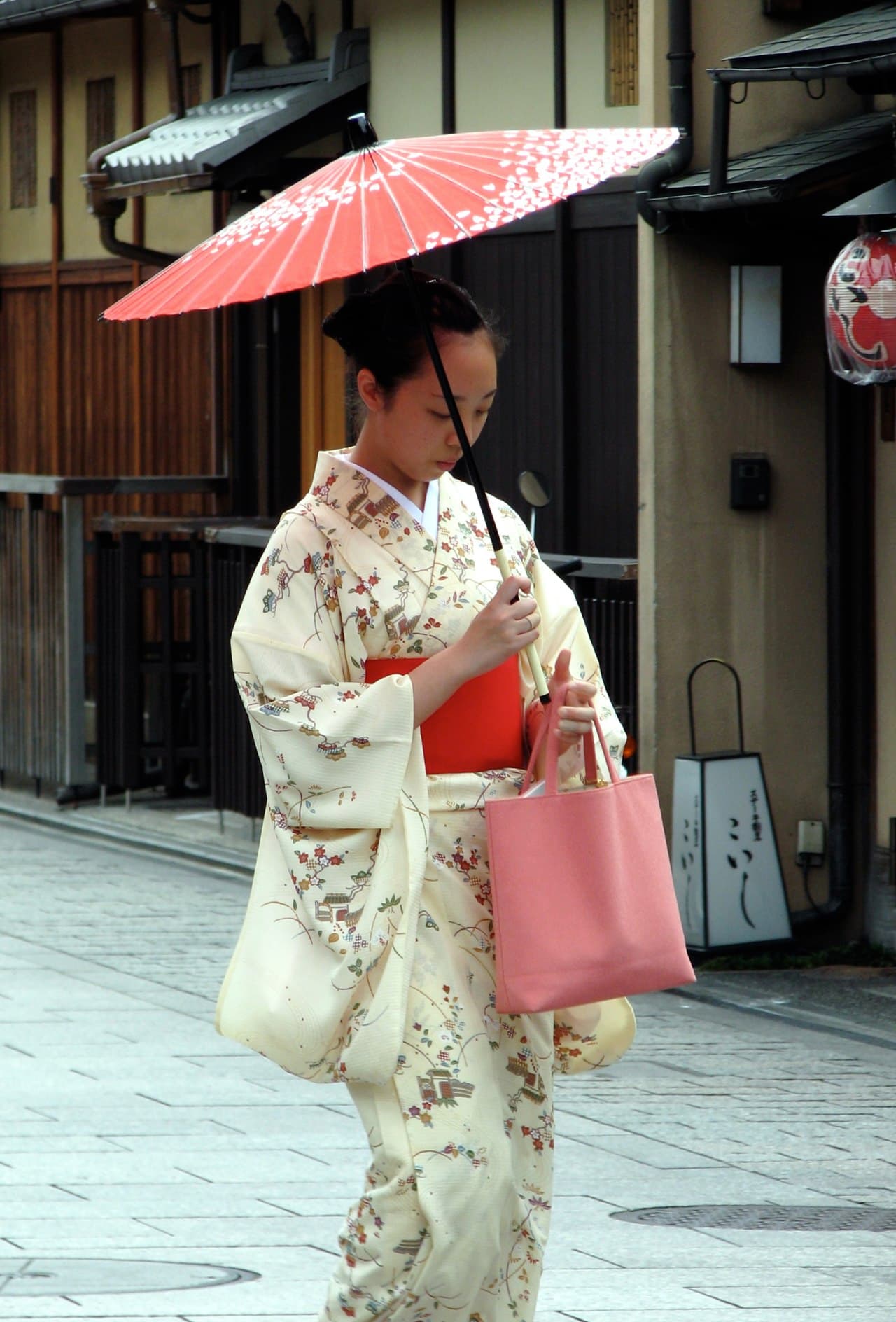 A woman in kimono walking a historic street in Kyoto's Gion district