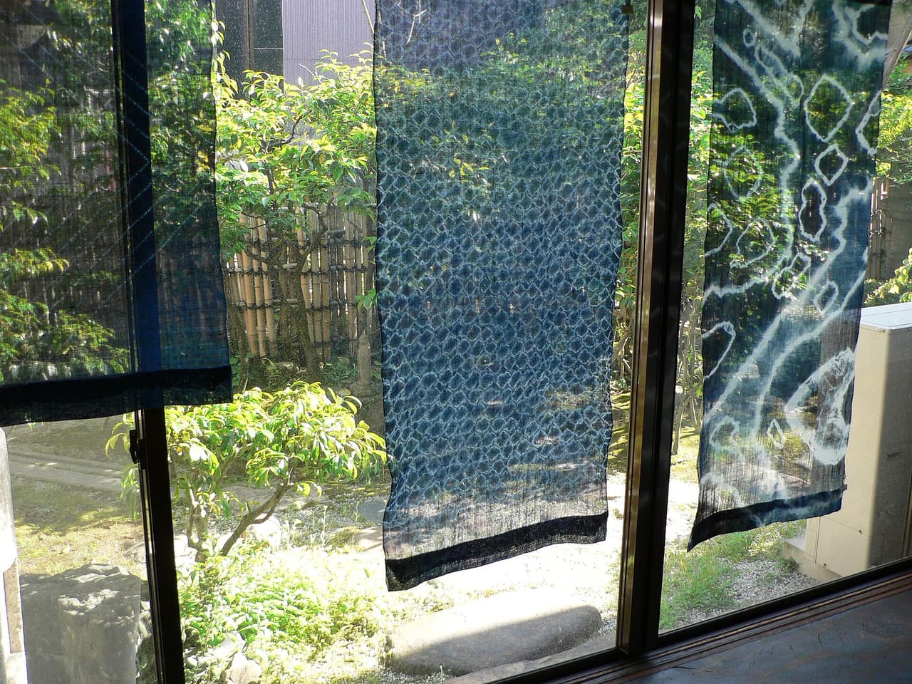 Sunlight filtering through tied-and-indigo-dyed shibori fabric, showing the resist pattern