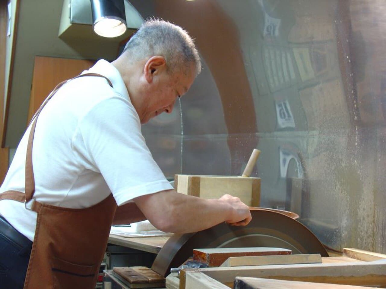 A craftsman sharpening a traditional Japanese kitchen knife by hand on a whetstone