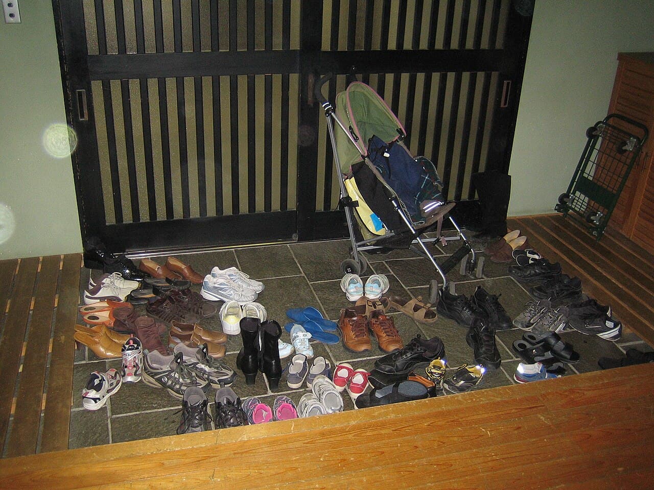 A sign asking visitors to leave their shoes at the entrance, next to a genkan-style doorway in Japan