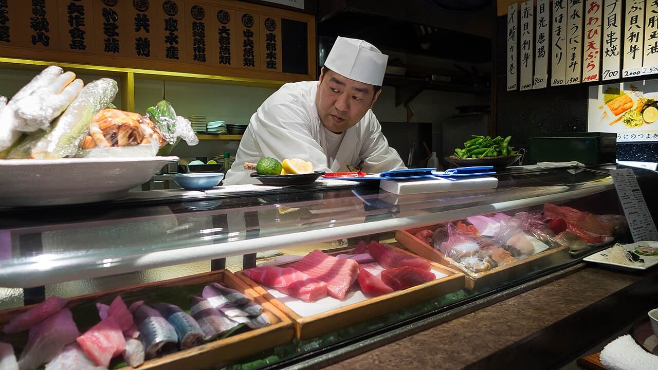 Un chef de sushi trabajando tras la barra de un restaurante de Tokio
