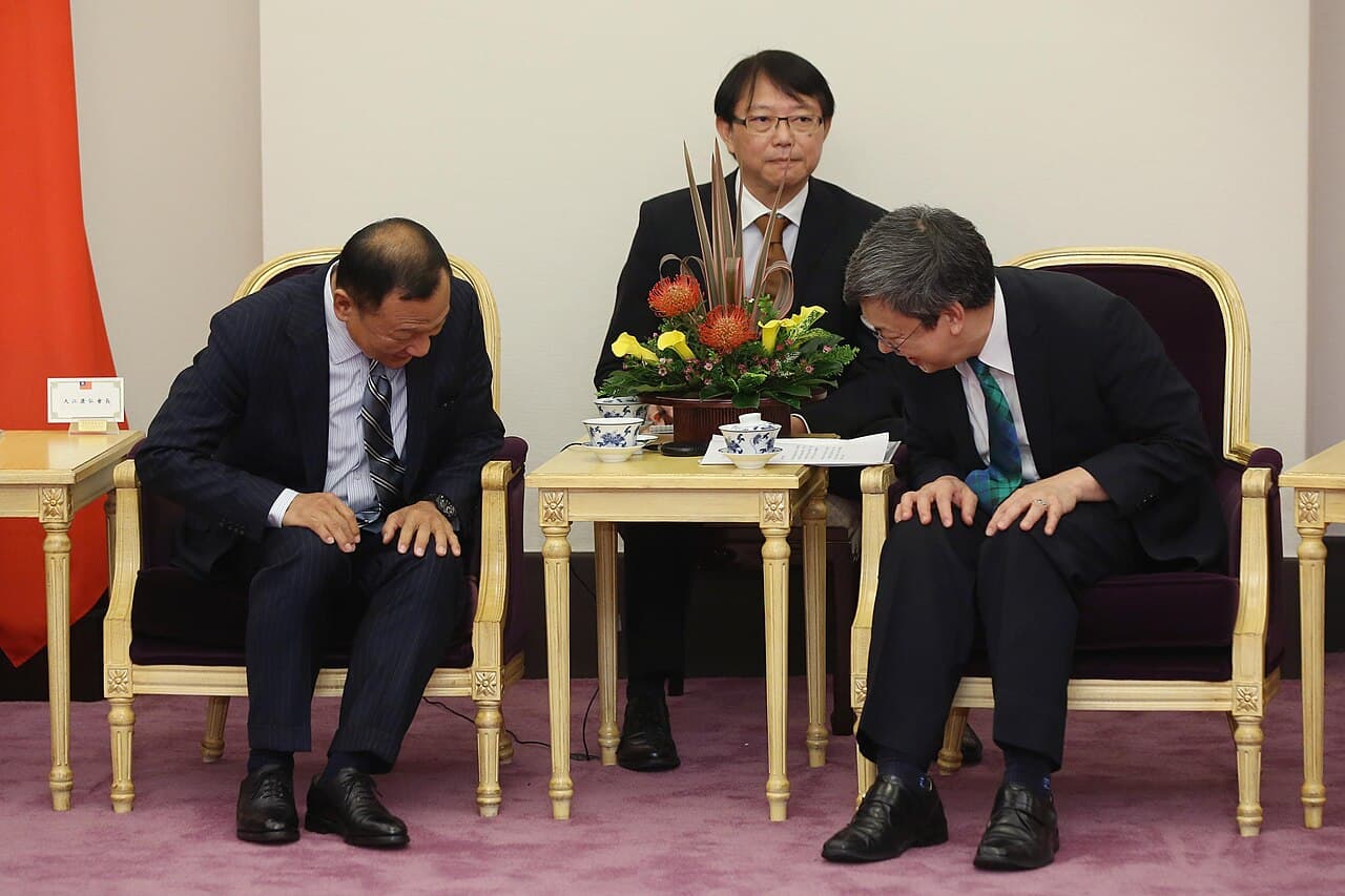 Two people exchanging a formal bow (ojigi) at a public greeting — the standard way to greet someone respectfully in Japan