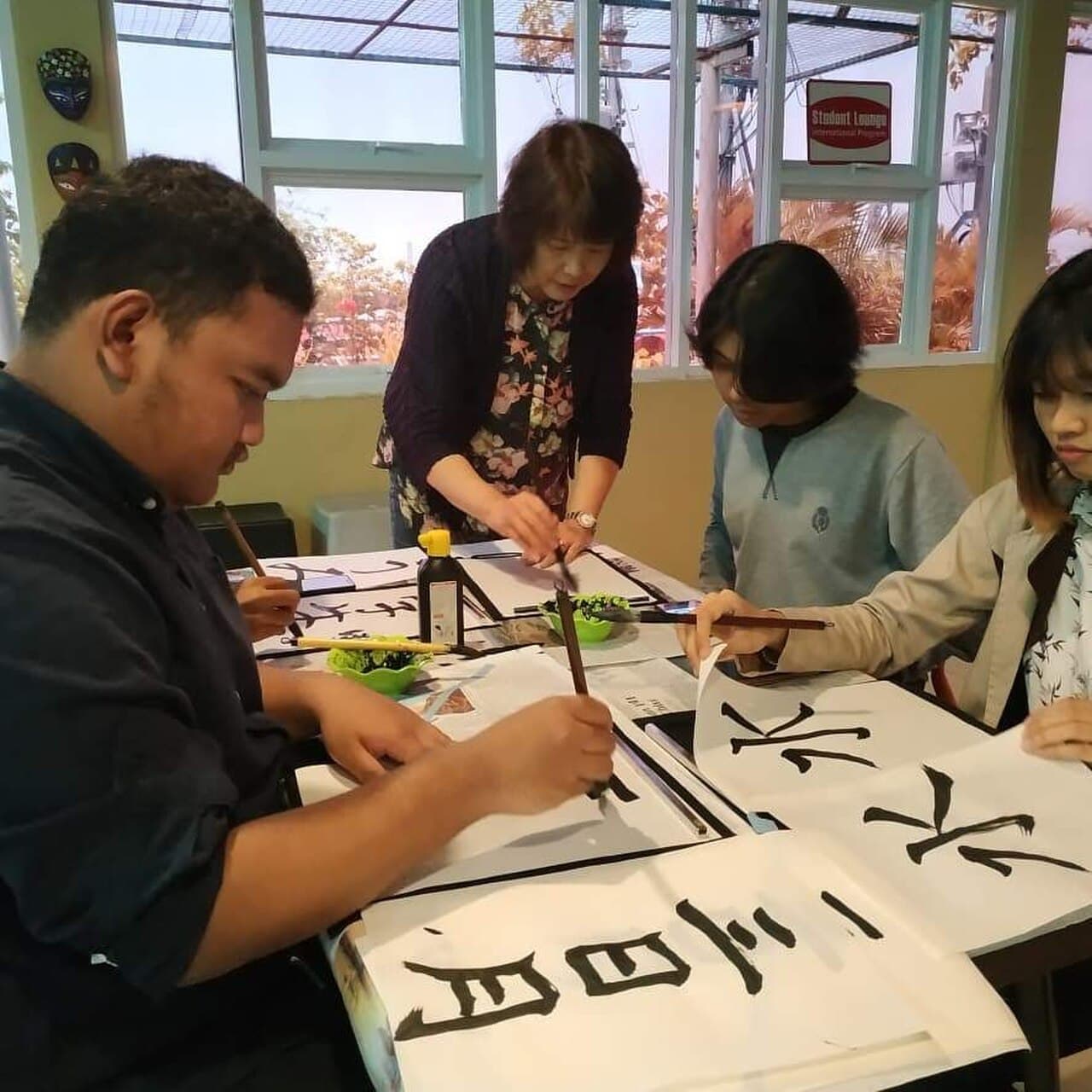 A hand writing Japanese kanji with an ink-loaded fude brush — shodō calligraphy in action