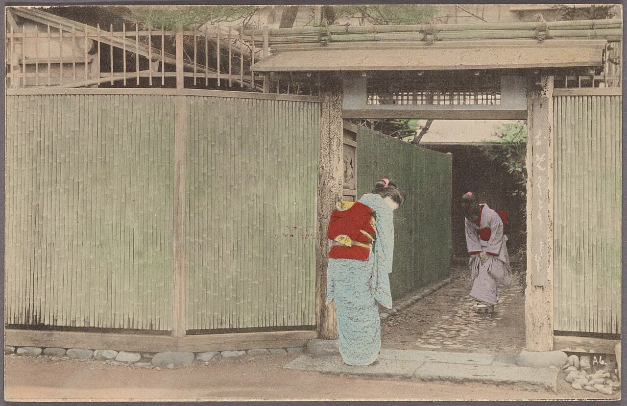 Two women bowing to each other in a Japanese entryway — a traditional gesture of greeting and hospitality