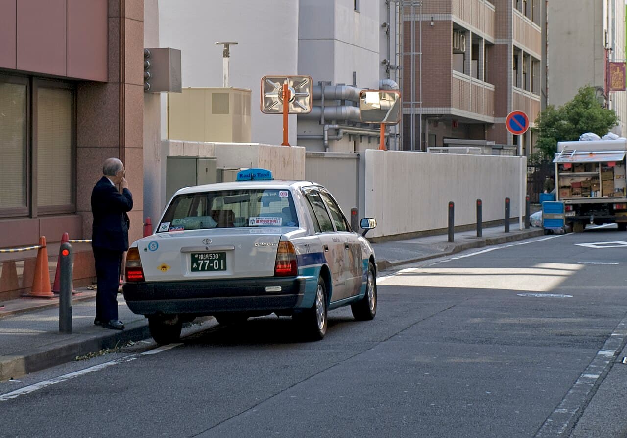 A taxi and driver on a street in Yokohama, Japan — tipping is not expected for everyday taxi rides