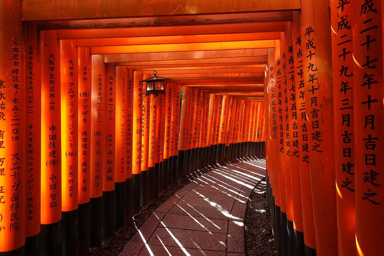 A row of vermilion torii gates forming a tunnel at Fushimi Inari Taisha, Kyoto