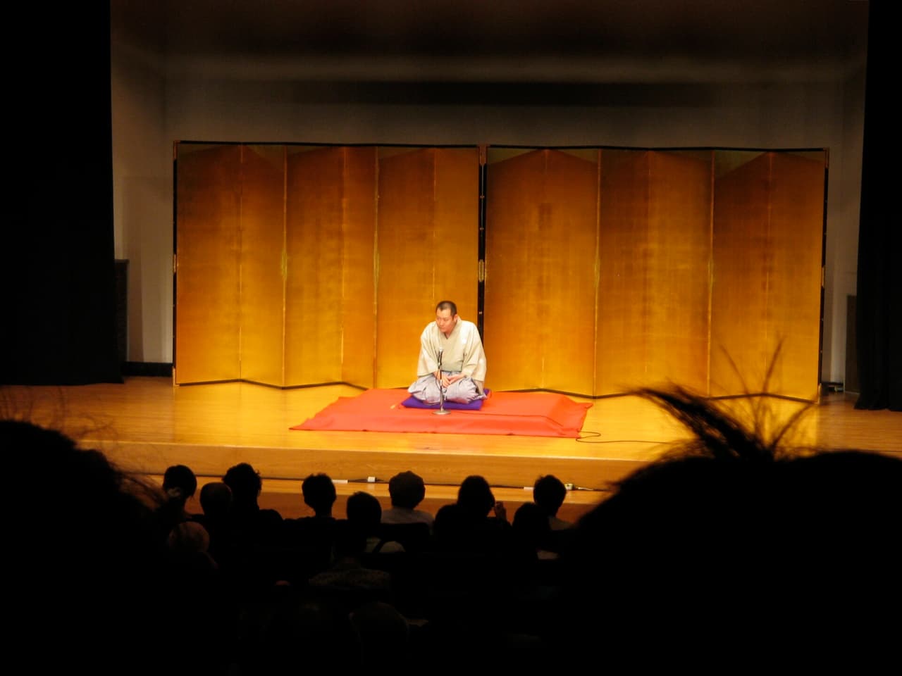 A rakugo storyteller performing seated on a cushion