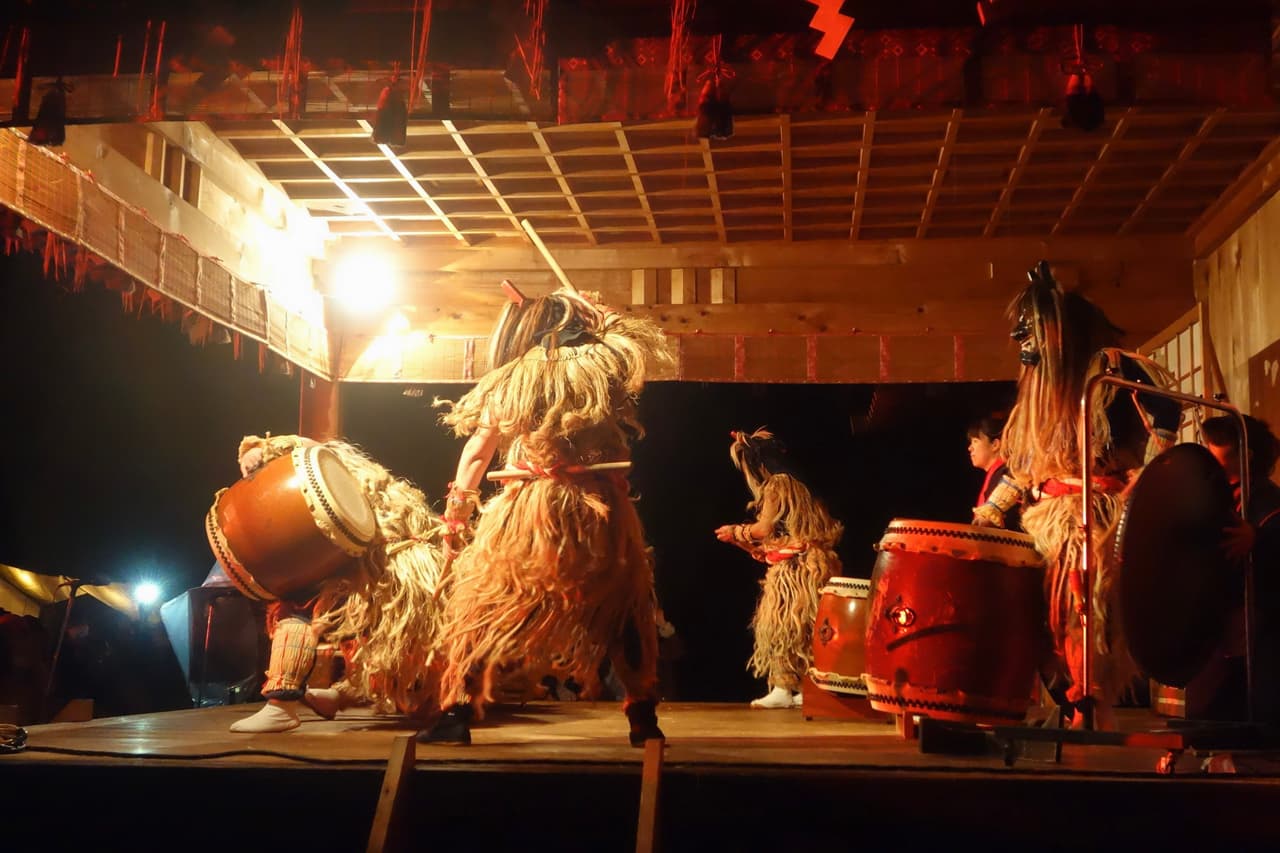 冬の祭りで、太い撥を使って和太鼓を打つ奏者たち