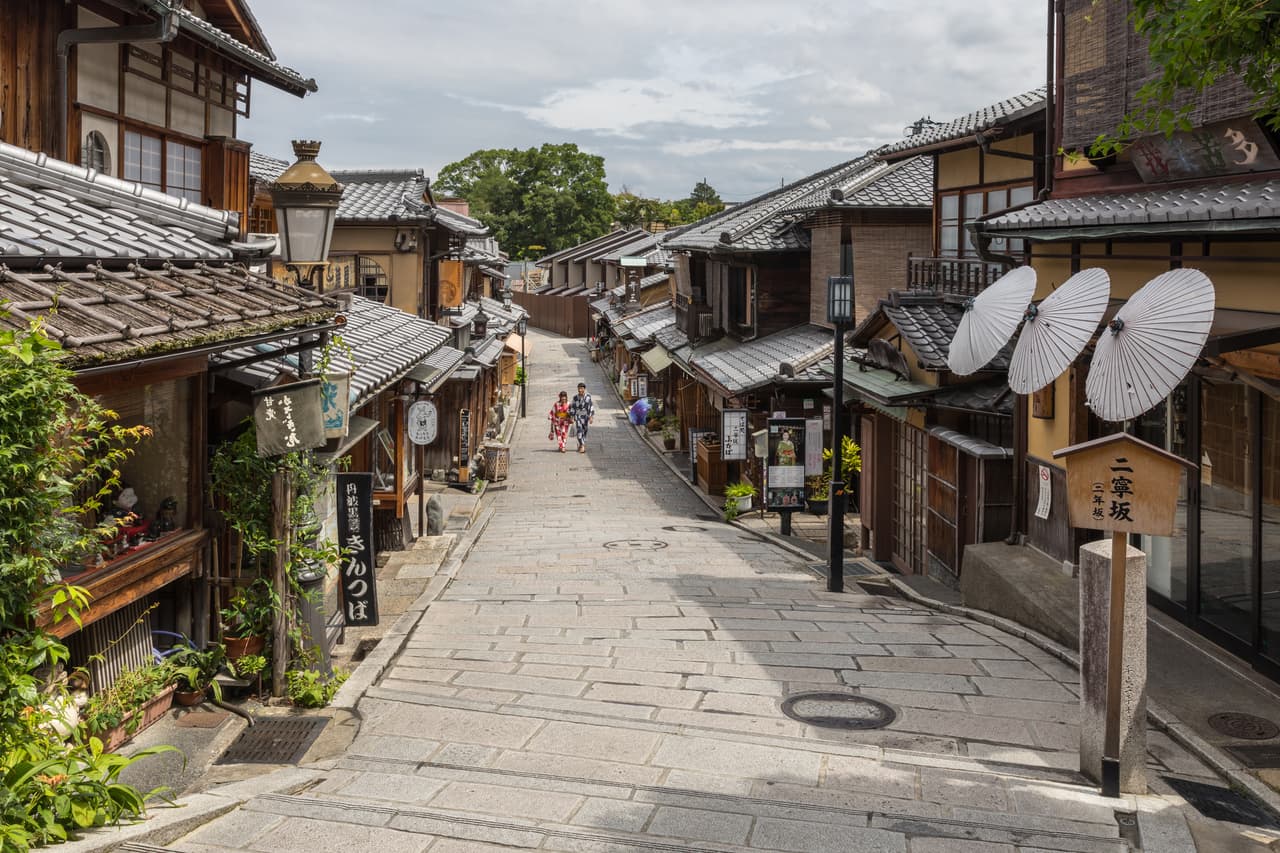 京都・東山の和傘が並ぶ通りを浴衣で歩く人々