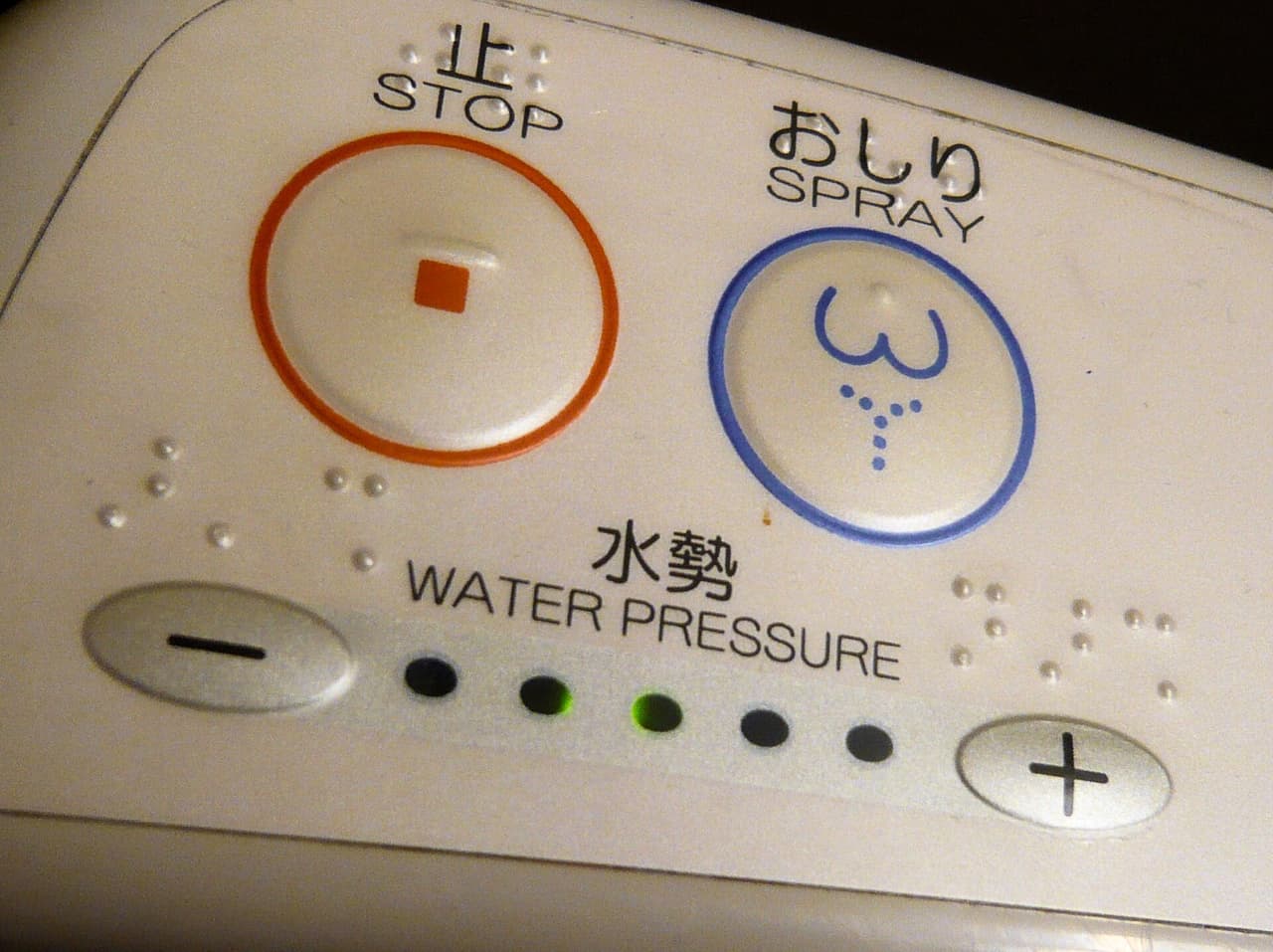 Close-up of a Japanese washlet control panel showing spray, bidet, dry and stop buttons