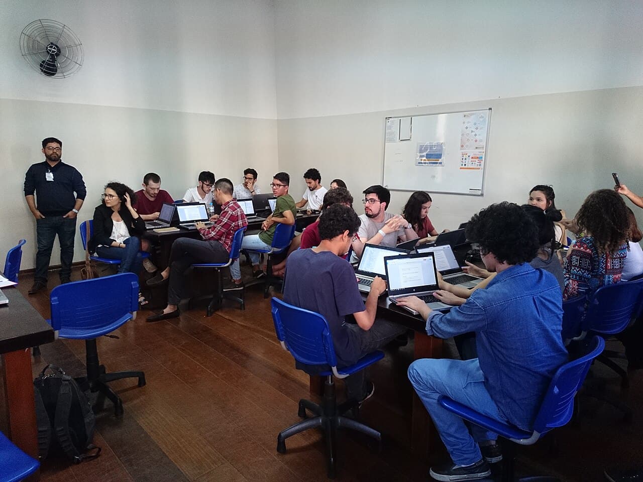 Volunteers cross-checking facts side by side with a magnifying glass and reference material during a fact-checking workshop